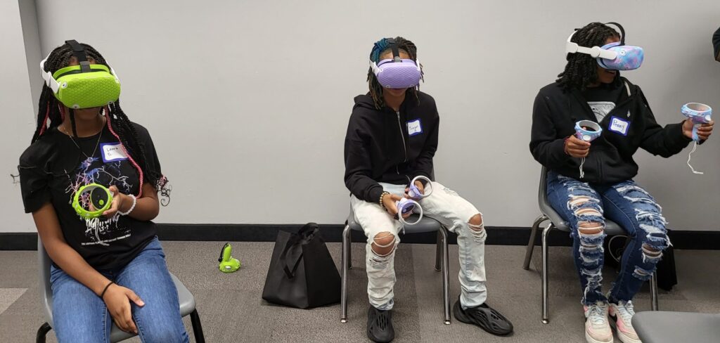 Three students wearing VR (Virtual Reality) Headsets at a QUED-UP Event