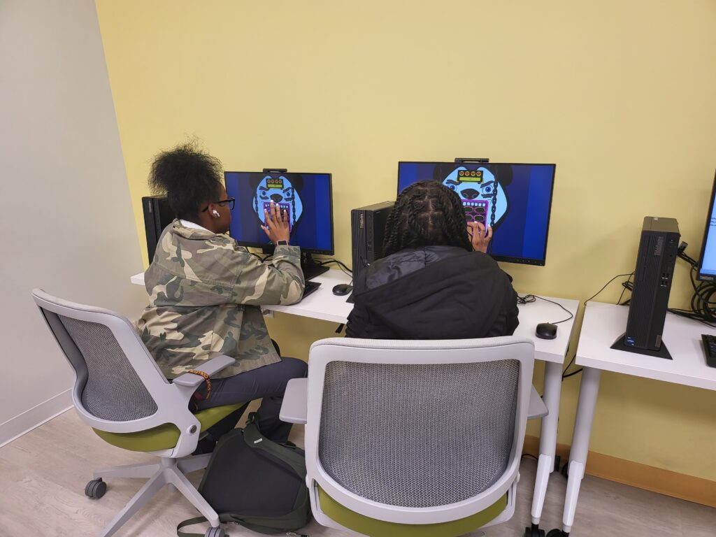 two female students at a QUED-UP workshop exploring a game called Pound the Pandas